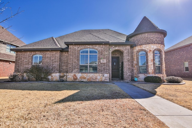 french country home with stone siding, a front yard, and brick siding