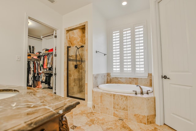 full bath with a walk in closet, a garden tub, visible vents, a shower stall, and tile patterned floors