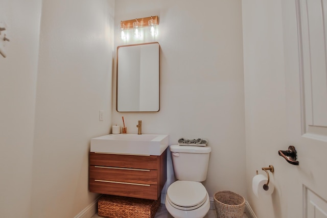 half bath with toilet, vanity, and baseboards