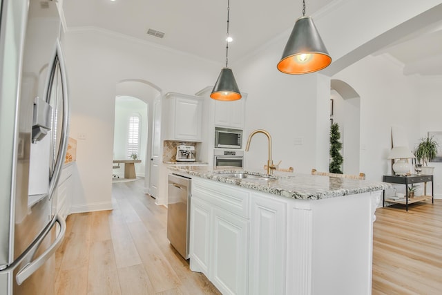 kitchen featuring arched walkways, crown molding, visible vents, appliances with stainless steel finishes, and a sink