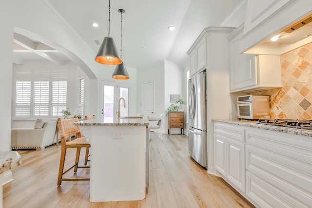 kitchen featuring light stone counters, light wood-style floors, appliances with stainless steel finishes, backsplash, and custom range hood