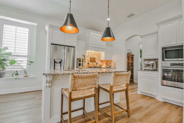 kitchen featuring decorative backsplash, appliances with stainless steel finishes, arched walkways, and crown molding