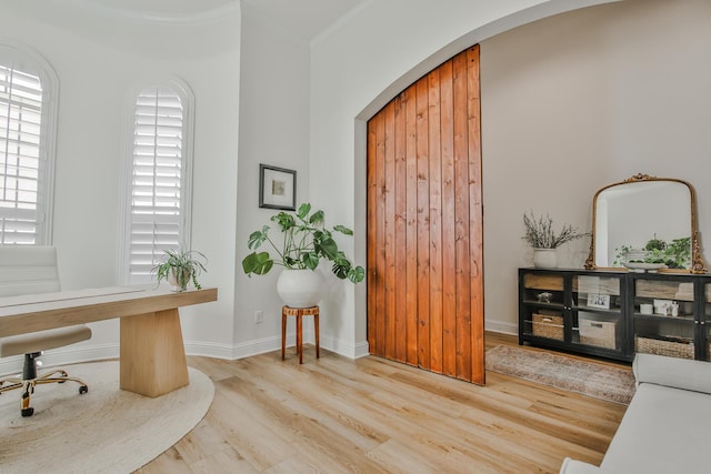 office area featuring baseboards, crown molding, arched walkways, and wood finished floors