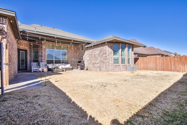 rear view of property with a shingled roof, a patio area, brick siding, and fence