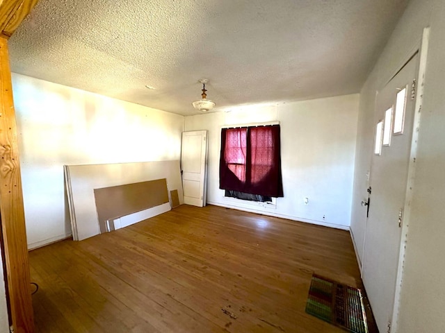 unfurnished room with hardwood / wood-style flooring and a textured ceiling