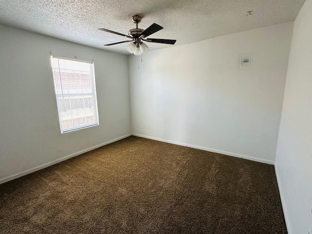 empty room featuring ceiling fan, dark carpet, and a textured ceiling