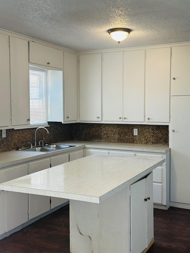 kitchen featuring a kitchen island, sink, dark wood-type flooring, and white cabinets