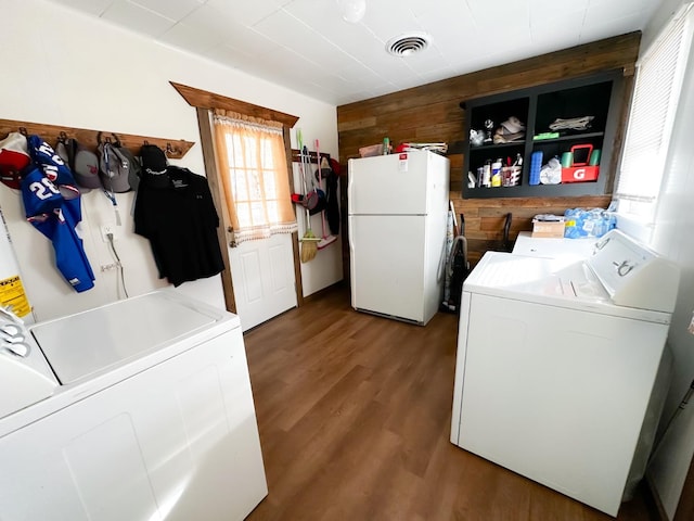 washroom with hardwood / wood-style floors, washer and clothes dryer, and wood walls