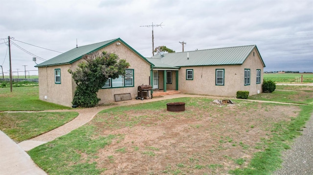 back of house with an outdoor fire pit and a lawn