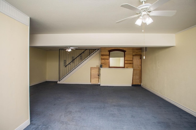 unfurnished room with baseboards, dark carpet, stairway, and a ceiling fan