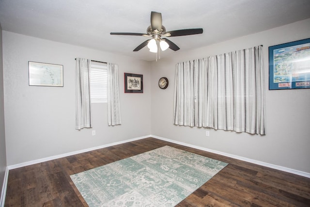 empty room with baseboards, dark wood-style flooring, and ceiling fan