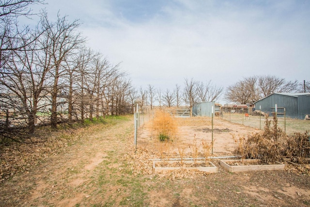 view of yard with an outbuilding, fence, a vegetable garden, and a pole building