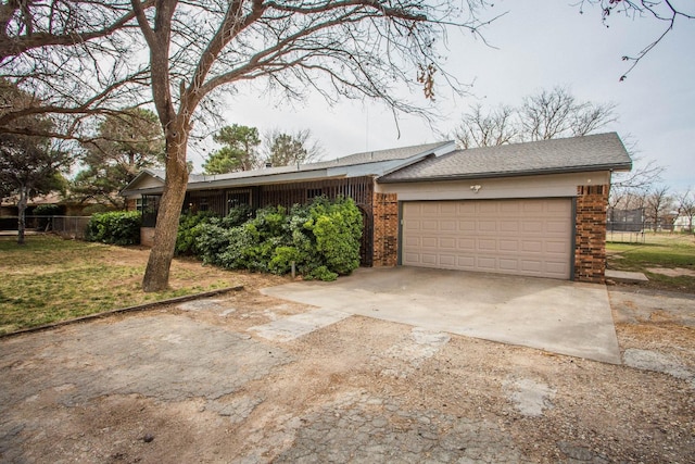 view of front of property with fence, a garage, a front yard, brick siding, and driveway