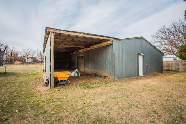 view of pole building with a lawn, fence, a trampoline, and a carport