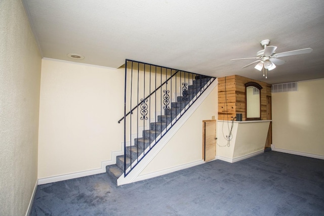 basement featuring carpet flooring, ceiling fan, visible vents, and stairway