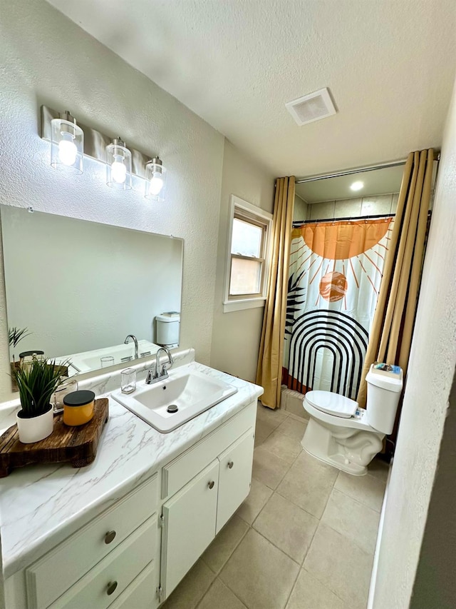 bathroom with a textured ceiling, a textured wall, tile patterned flooring, toilet, and vanity