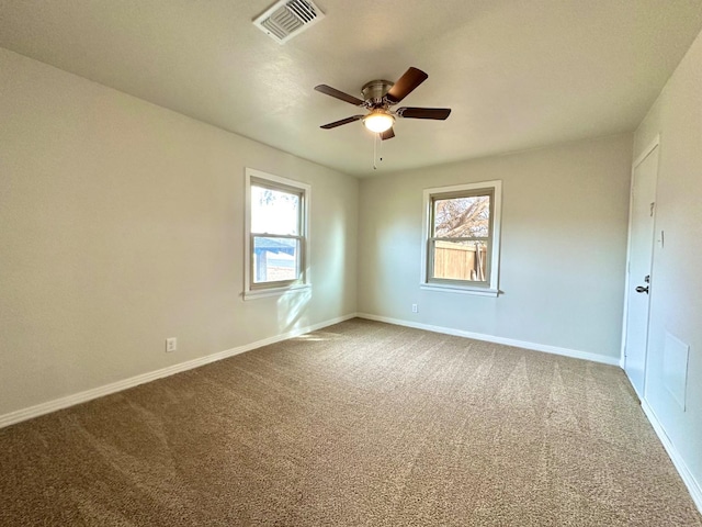 carpeted empty room featuring baseboards, visible vents, and ceiling fan