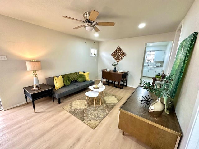 living room with ceiling fan, wood finished floors, and baseboards