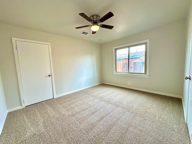 spare room featuring a ceiling fan, carpet, visible vents, and baseboards