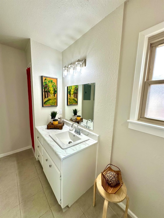 bathroom with a textured ceiling, baseboards, vanity, and tile patterned floors