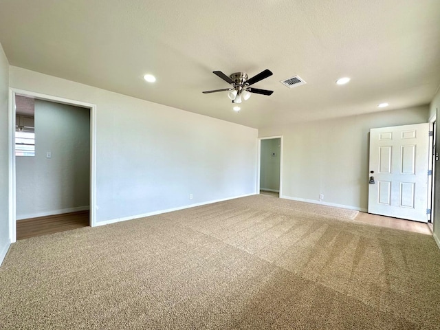 spare room featuring carpet floors, ceiling fan, visible vents, and baseboards