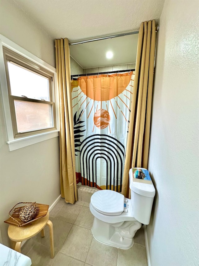 full bathroom with a shower with shower curtain, tile patterned flooring, baseboards, and toilet