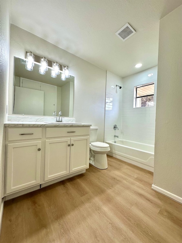 full bath with toilet, wood finished floors, vanity, visible vents, and tub / shower combination