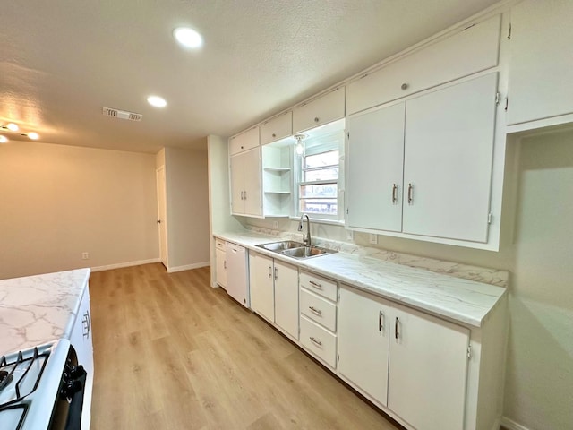 kitchen featuring white dishwasher, a sink, white cabinetry, light countertops, and light wood finished floors