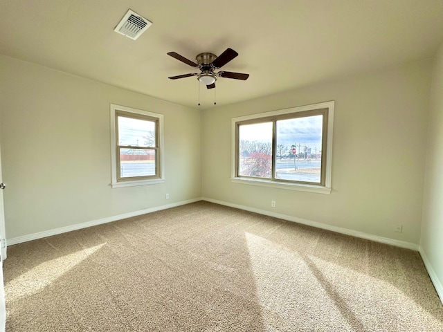 carpeted empty room featuring baseboards, visible vents, and a ceiling fan