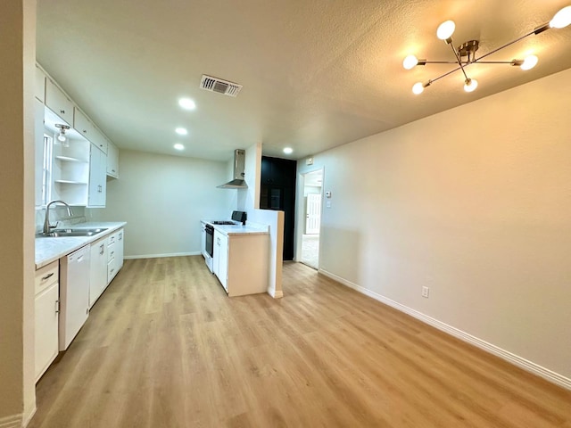 kitchen featuring white appliances, visible vents, light countertops, wall chimney range hood, and a sink