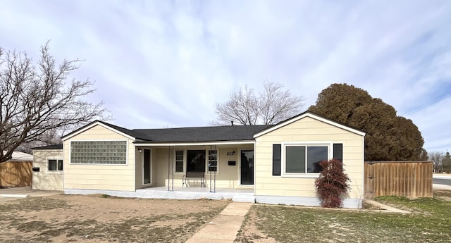 ranch-style house featuring covered porch and fence