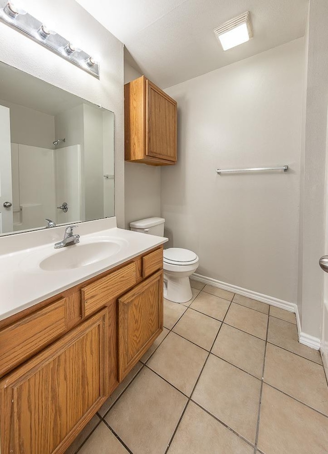 bathroom featuring tile patterned flooring, vanity, toilet, and walk in shower