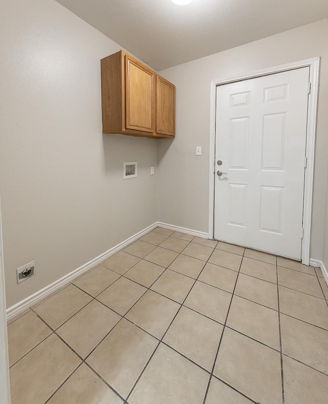 clothes washing area with cabinets, washer hookup, and light tile patterned floors