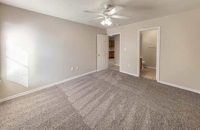 unfurnished bedroom with connected bathroom, a spacious closet, light colored carpet, a closet, and ceiling fan