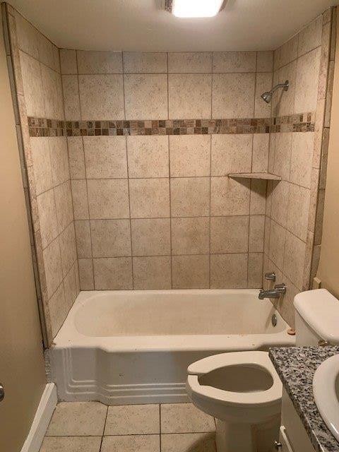 full bathroom featuring tiled shower / bath, vanity, toilet, and tile patterned flooring