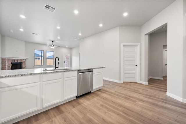 kitchen with dishwasher, sink, white cabinets, and light stone counters