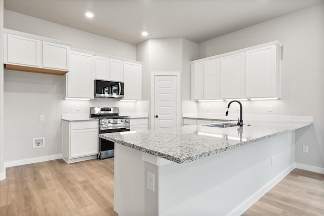 kitchen with sink, white cabinets, kitchen peninsula, stainless steel appliances, and light hardwood / wood-style flooring