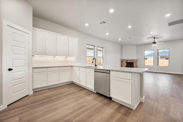 kitchen featuring light stone counters, a wealth of natural light, white cabinets, stainless steel dishwasher, and light wood-type flooring