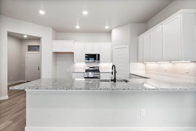 kitchen with sink, light hardwood / wood-style flooring, white cabinetry, stainless steel appliances, and kitchen peninsula