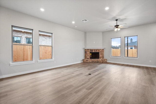 unfurnished living room with ceiling fan, a fireplace, and light hardwood / wood-style floors