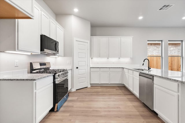 kitchen with sink, appliances with stainless steel finishes, light stone countertops, light hardwood / wood-style floors, and white cabinets