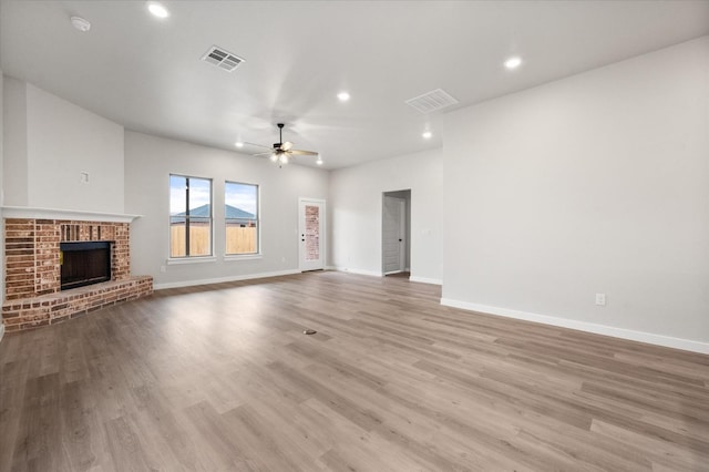 unfurnished living room featuring a brick fireplace, ceiling fan, and light wood-type flooring