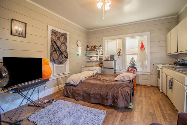 bedroom with crown molding, ceiling fan, wood-type flooring, and wooden walls