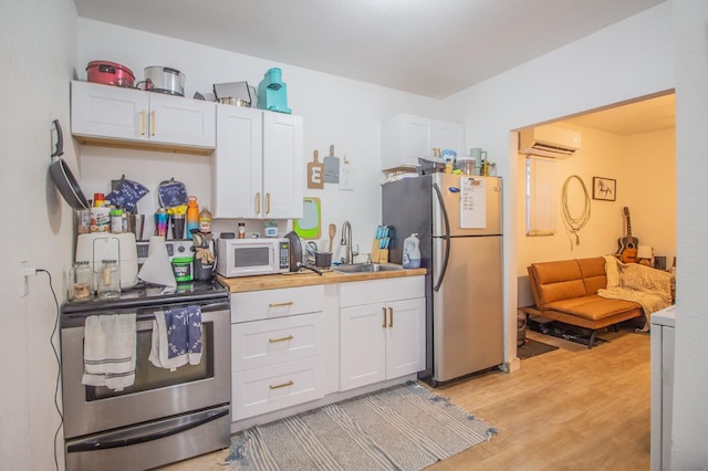 kitchen featuring white cabinetry, light hardwood / wood-style floors, a wall mounted AC, and appliances with stainless steel finishes