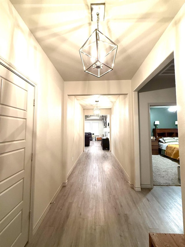 corridor featuring hardwood / wood-style flooring and a notable chandelier