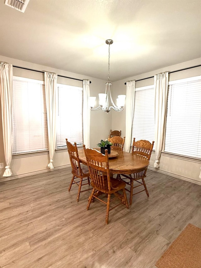 dining space featuring wood-type flooring and a notable chandelier