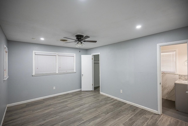 unfurnished bedroom with connected bathroom, hardwood / wood-style floors, and ceiling fan