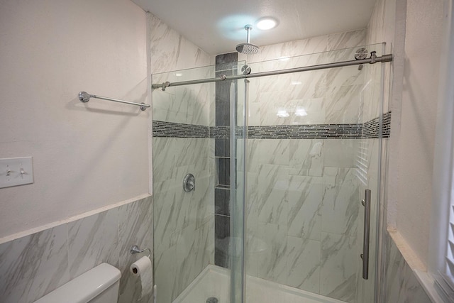 bathroom featuring a shower with shower door and toilet