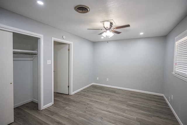 unfurnished bedroom with a closet, dark hardwood / wood-style floors, and ceiling fan