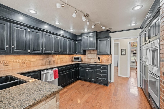 kitchen featuring light stone counters, crown molding, tasteful backsplash, light wood-type flooring, and appliances with stainless steel finishes